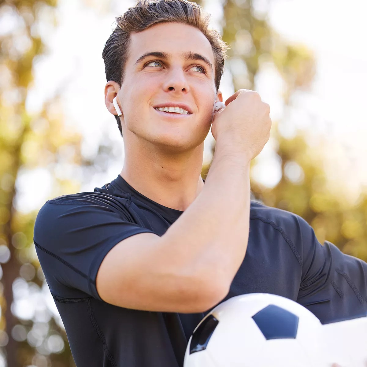 Teen boy with clear braces holding a soccer ball, smiling confidently—demonstrating how braces seamlessly fit into his active lifestyle while improving his smile.