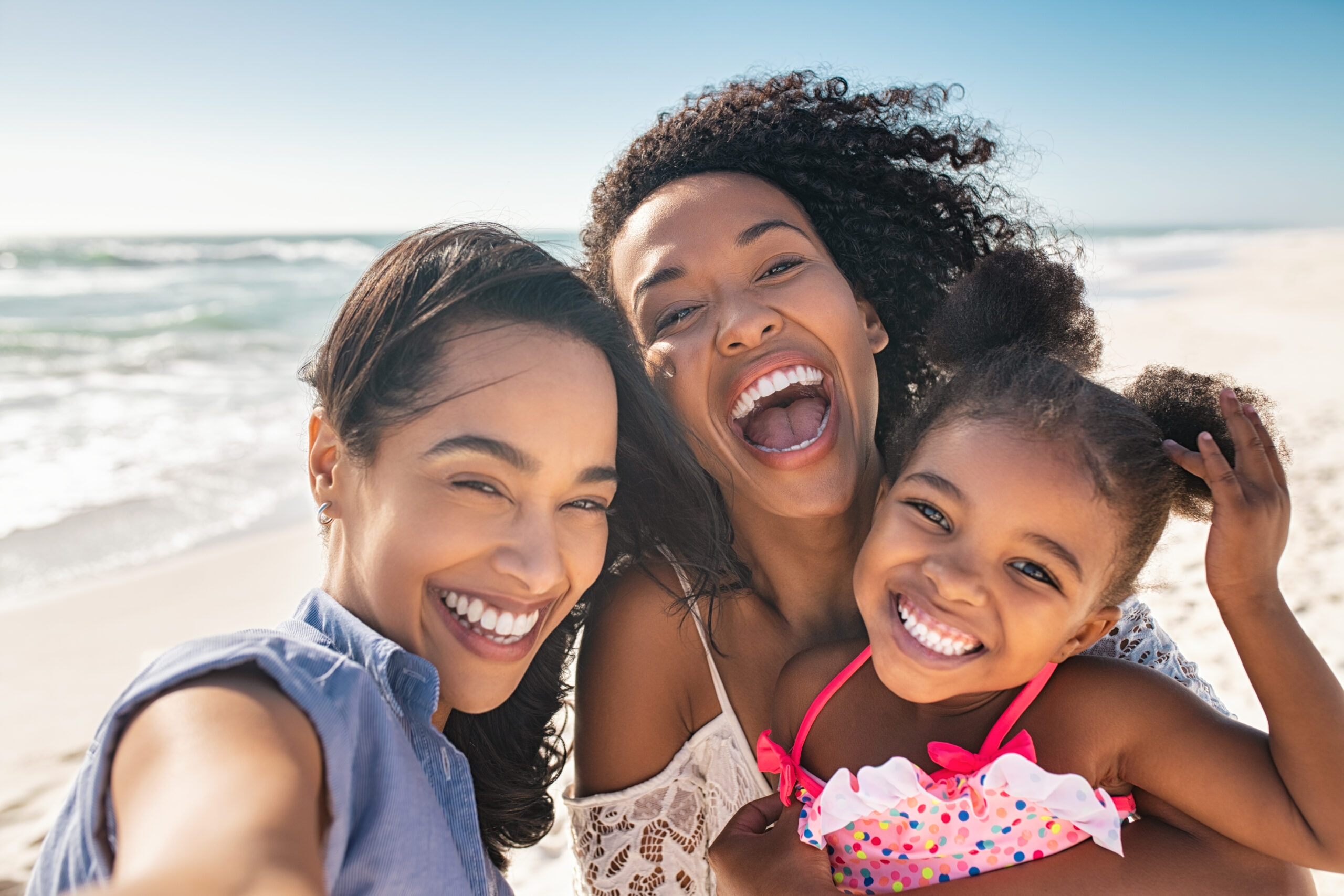 Family at beach smiling taking selfie Smiling family enjoying a day at the beach, proudly showing off the healthy, beautiful smiles made possible through orthodontic care.