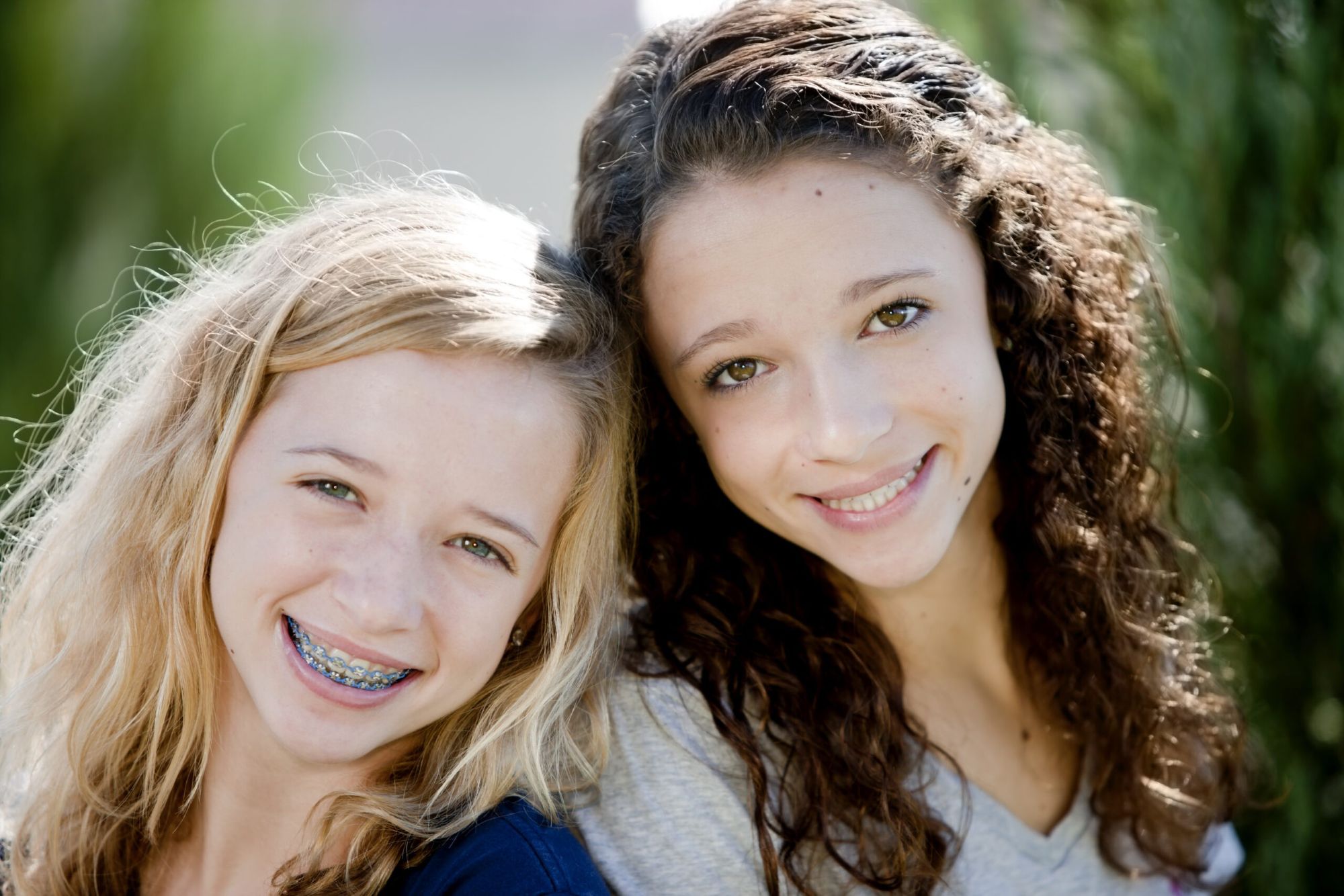 smiling teenage girls braces Two smiling teenagers, one wearing braces, happily embracing her personalized orthodontic journey and the confidence it brings