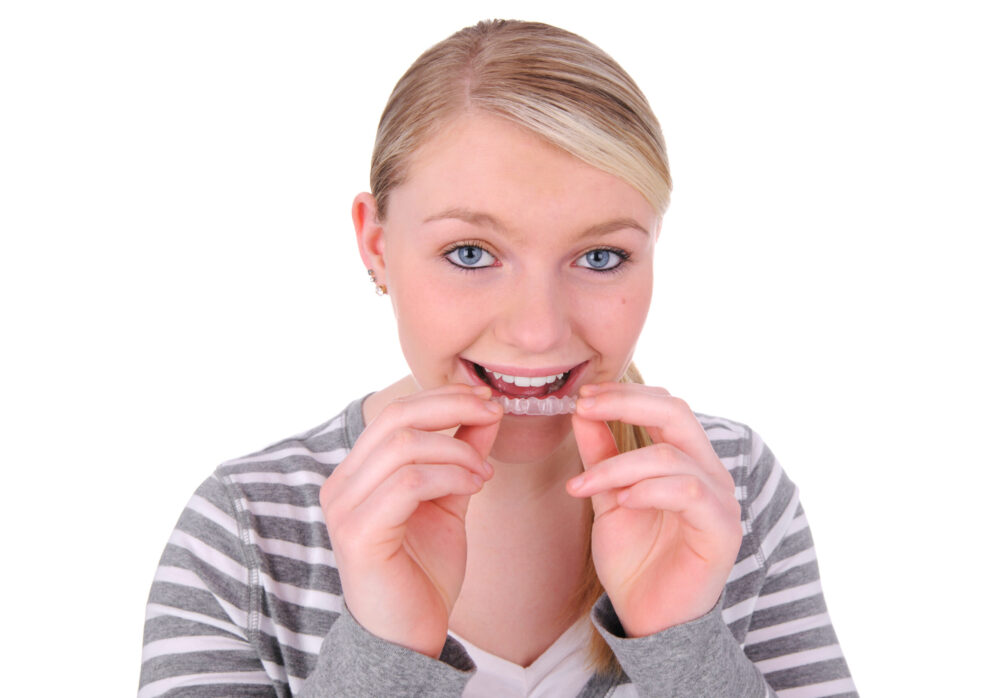 teen girl wearing clear aligners Teenager wearing clear aligners and smiling with confidence, showing how orthodontic treatment supports oral health while boosting self-esteem.